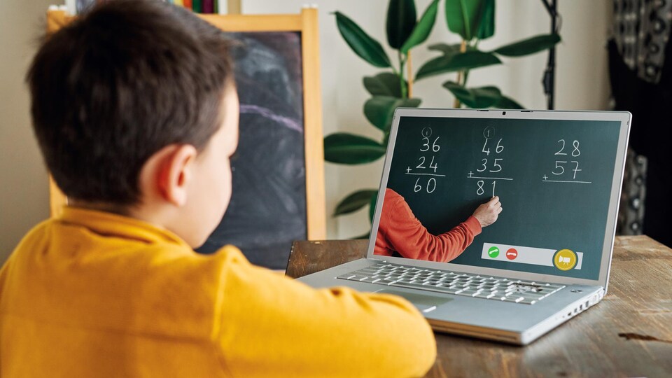 Un enfant devant son ordinateur portable avec, sur l'écran, des exemples d'additions.