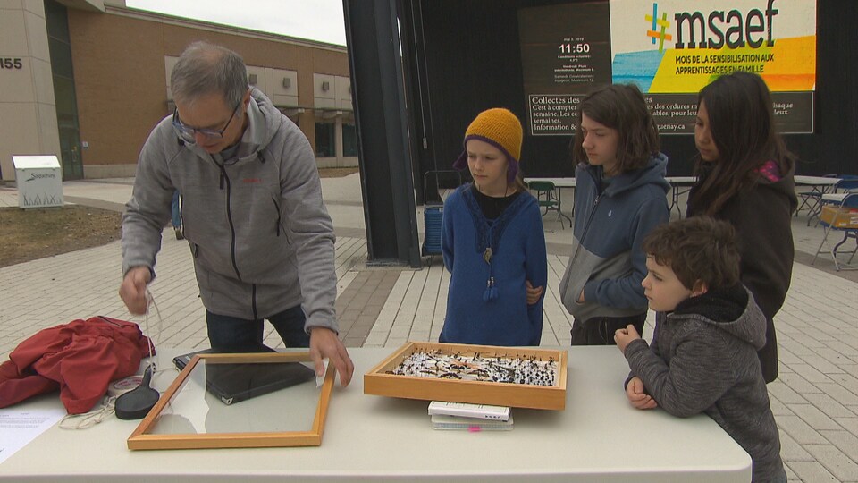 Un homme anime un atelier alors que des enfants l'observent à la place du citoyen de Chicoutimi