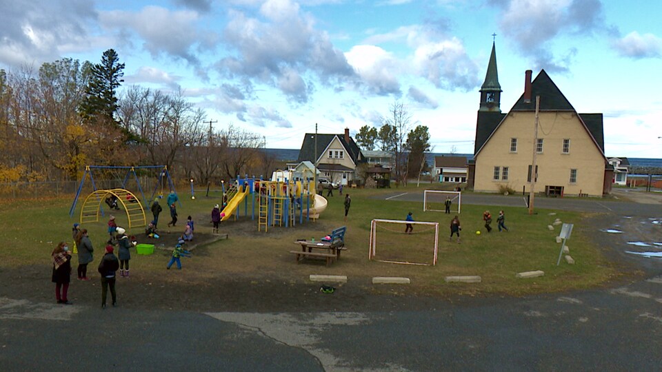 Les jeunes jouent dans l'espace entre l'école et l,église.