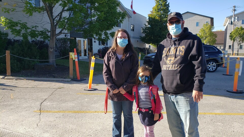 Un couple qui accompagne une petite fille à l’école.