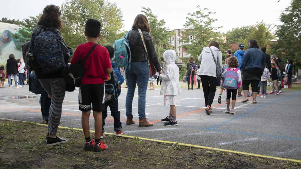 Des parents et des enfants dans une cour d'école.