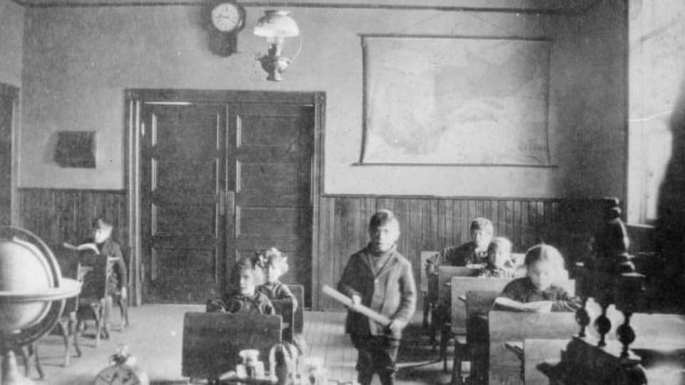 Un garçon se tient debout avec un bâton dans les mains, au milieu d'une classe.