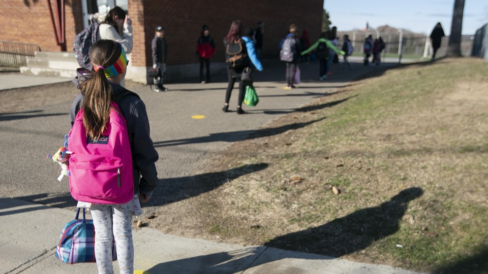 Des enfants gardent une bonne distance entre eux avant d'entrer dans une école.