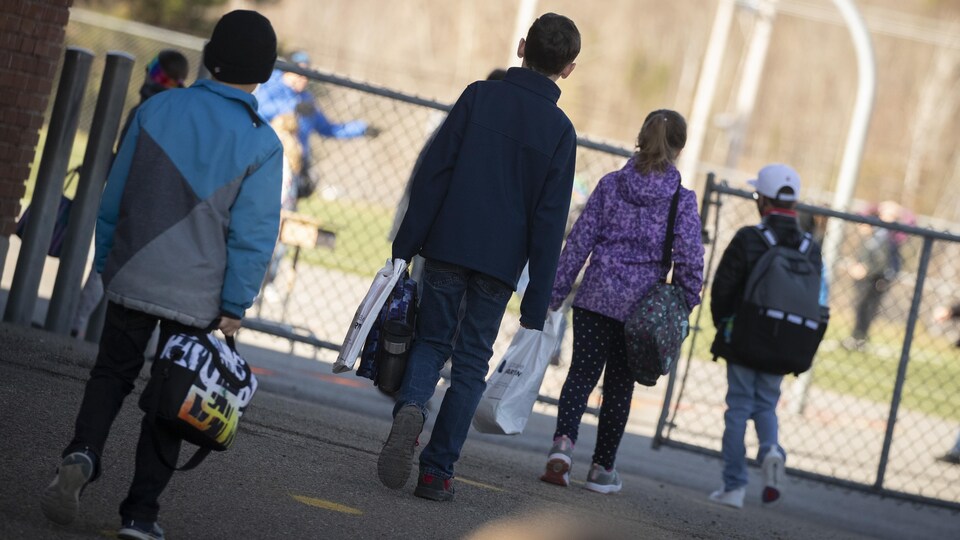 Des enfants gardent une bonne distance entre eux avant d'entrer dans une école.