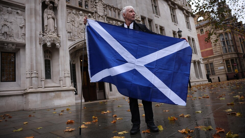 Un homme porte un drapeau écossais