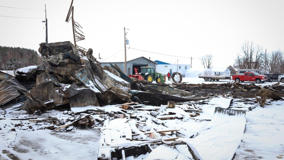Amoncellement de débris d'une écurie ravagée par un incendie, en hiver.