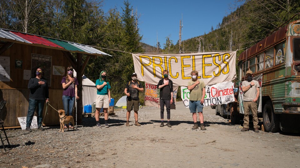 Sept manifestants se tiennent devant des bannières.