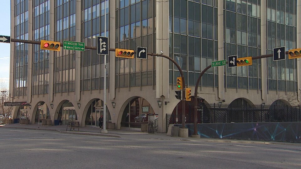 Un coin de rue au centre-ville de Calgary. On voit un édifice commercial avec des arches sur la rue en arrière-plan.