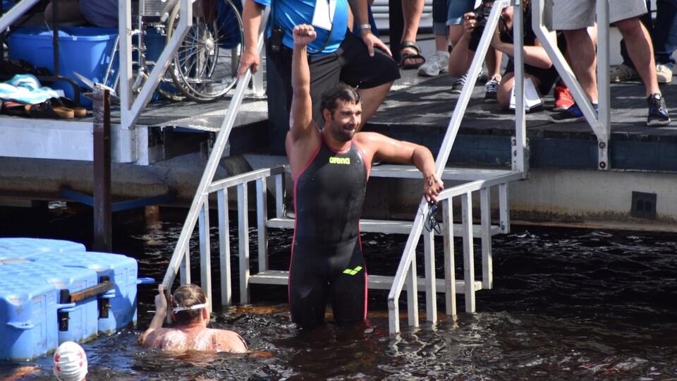 Un nageur soulève le bras en signe de victoire.