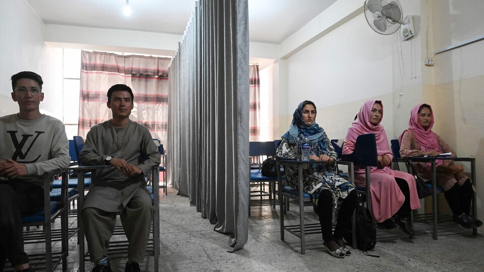 Un salle de classe avec des hommes à gauche et des femmes à droite. Un rideau les sépare.