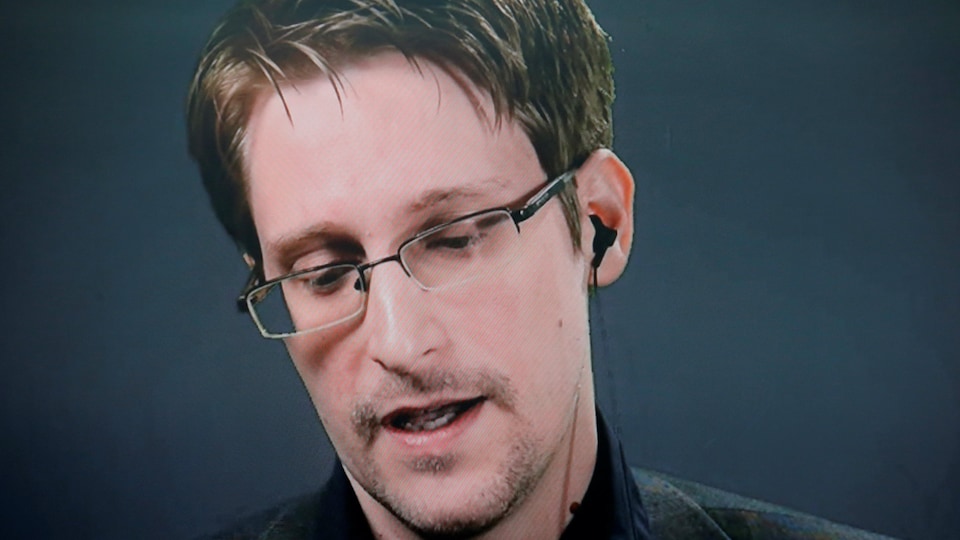 Edward Snowden, portant des lunettes, regardant vers le bas, au cours d'une allocution prononcée par vidéoconférence.