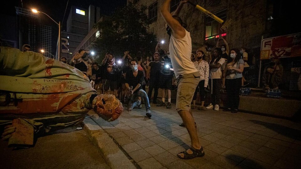 Un homme frappe une statue avec une massue.