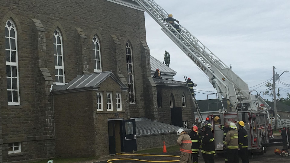 Les pompiers au travail s'affairent à monter sur le toit de l'église. 