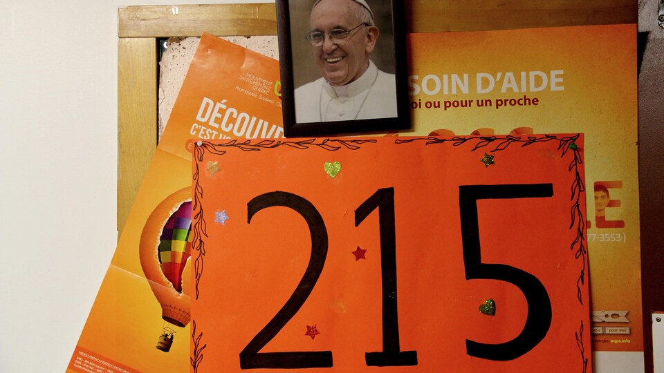 Une photo du pape François et une affiche indiquant le chiffre « 215 » en référence aux sépultures découvertes à Kamloops.