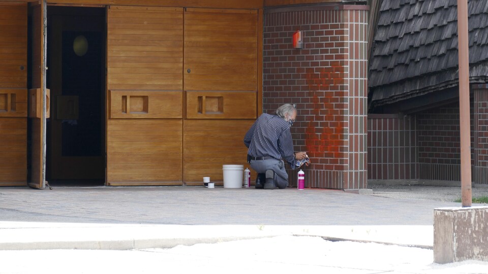 Un homme nettoie du graffiti sur les murs extérieurs d'une église de Winnipeg.