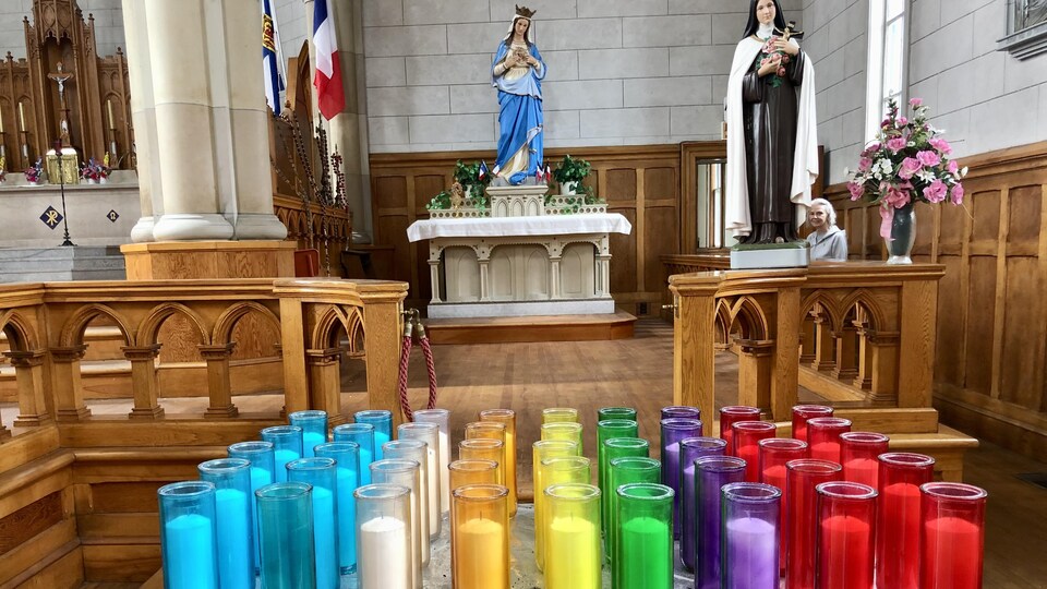 Des rangées de cierges dans des pots de vitre multicolores.
