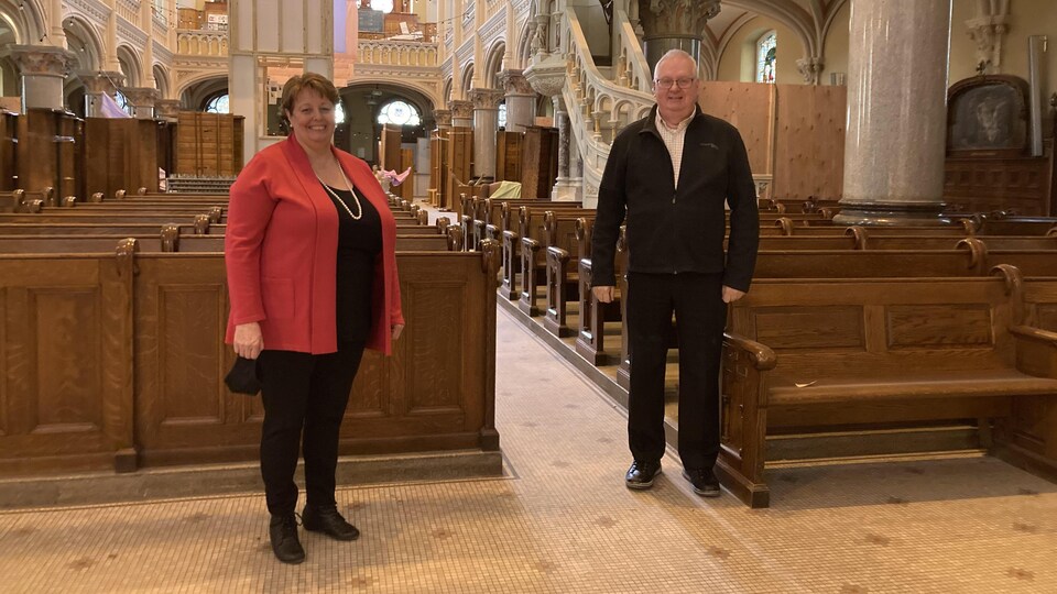 Une femme et un homme sourient à la caméra dans l'église en rénovations.