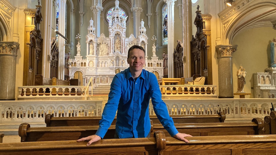 Un homme vêtu d'une chemise bleue devant l'autel de l'église Saint-Charles-de-Limoilou.