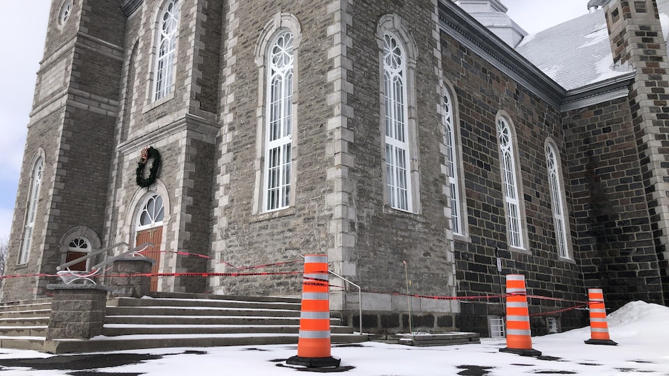 Des cônes orange bloquent l'accès à l'entrée d'une église.