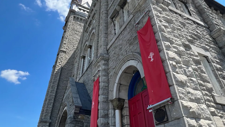 Des bannières rouges avec le logo de The United People of Canada sont accrochées à la façade de l'église Ste-Brigid.