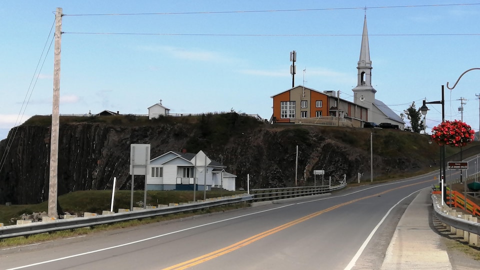Une église et un bâtiment adjacent sont au sommet d'une colline. Une route à 2 voies borde cette colline. 