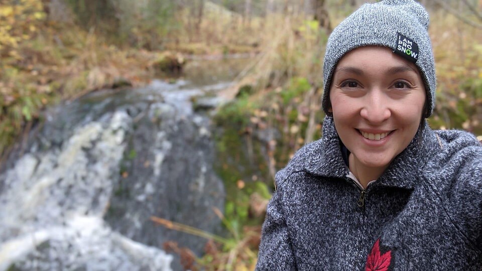 Elle pose à côté d'un ruisseau. 