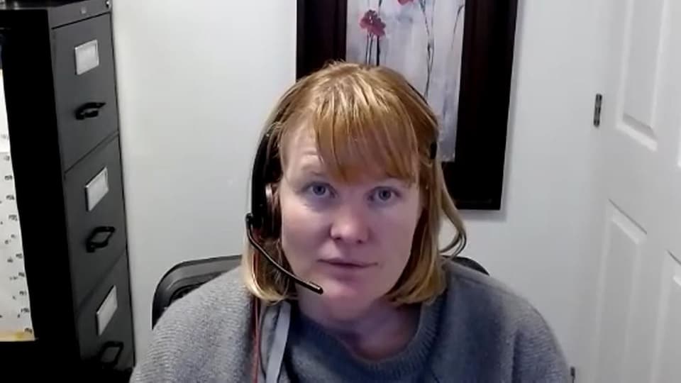 Eleanor Taylor portant un casque d'écoute, dans un bureau, en vidéoconférence.