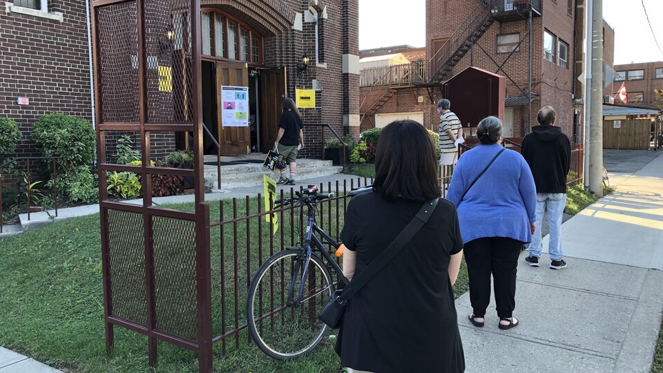 Des gens font la file devant le bureau de vote de la circonscription de Davenport, à Toronto, pour exercer leur droit de vote.