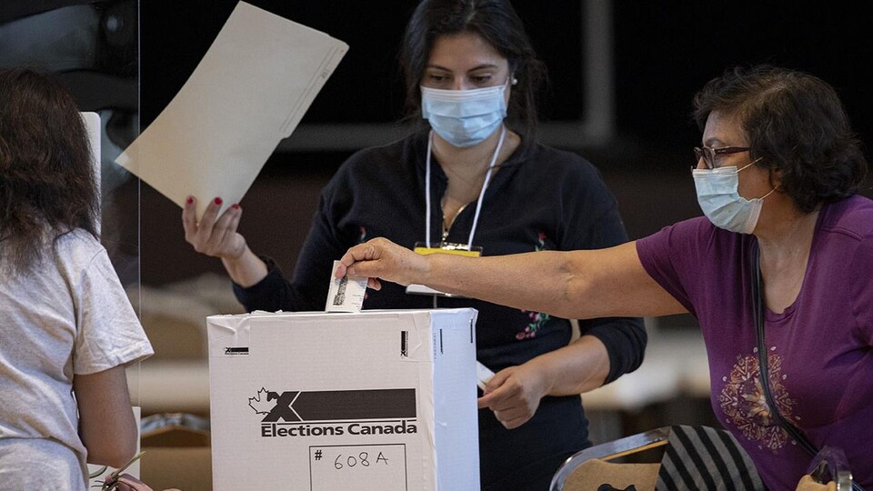 Une femme dépose son vote dans une boîte en carton.