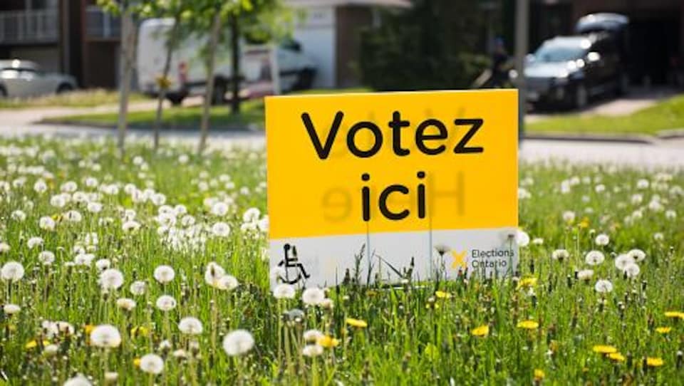 Une pancarte annonçant un bureau de vote plantée dans la pelouse.