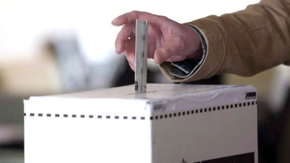 Un électeur dépose son bulletin dans une boîte de scrutin.