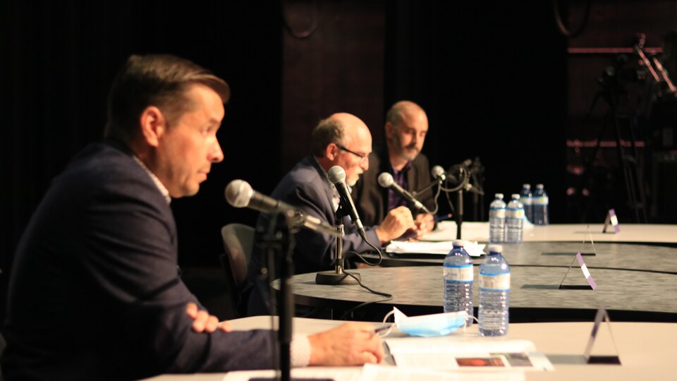 Dans l'ordre, Guy Bernatchez, Jean-Pierre Pigeon et Christian Rioux, tous assis devant un micro.