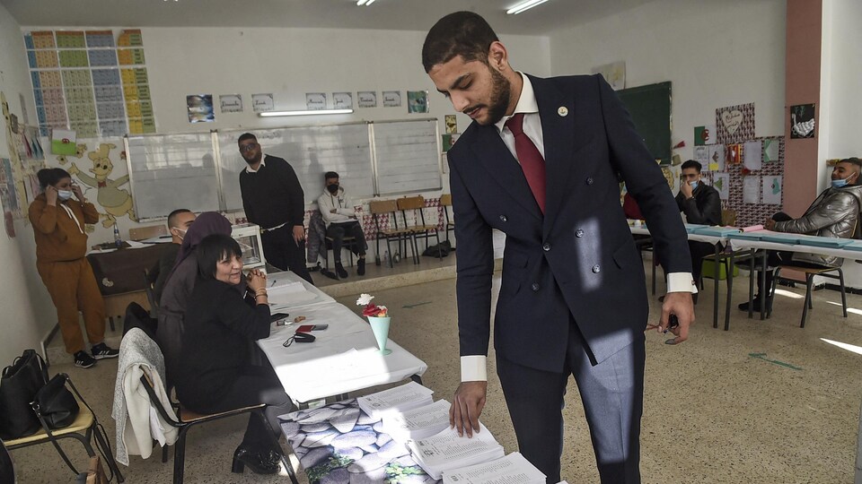 Un homme prend un bulletin de vote lors des élections locales algériennes.