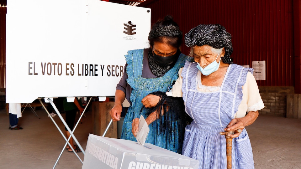 A woman puts her ballot in a box. 