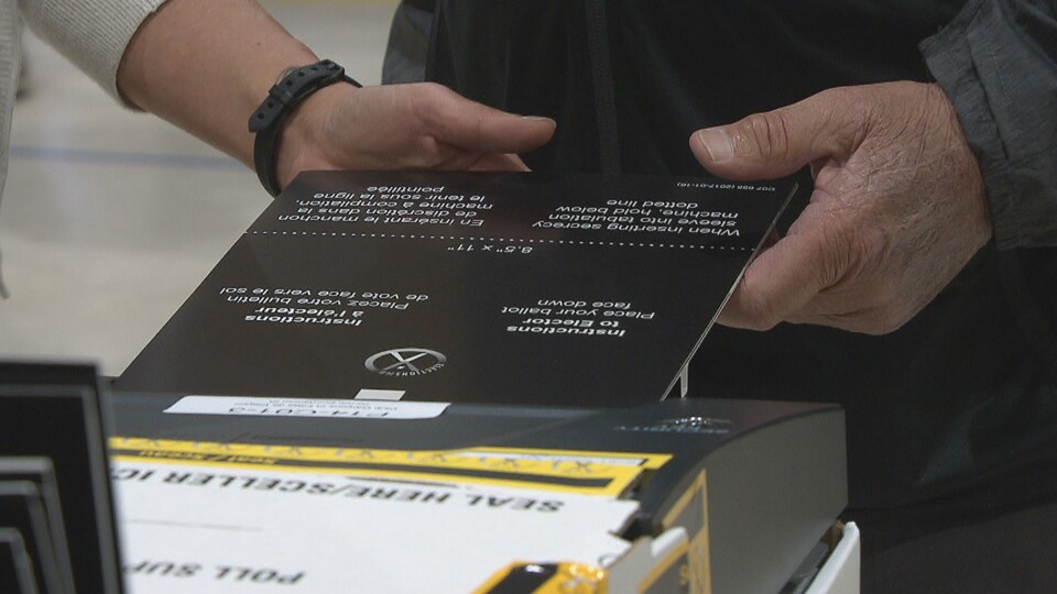 Un homme dépose son bulletin de vote dans une tabulatrice.