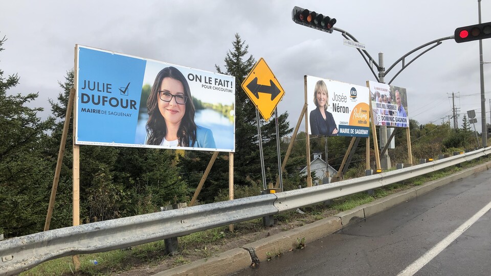 Trois pancartes électorales le long d'un boulevard.