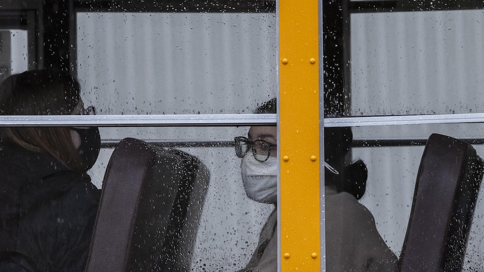 Une élève porte un masque dans un autobus scolaire.