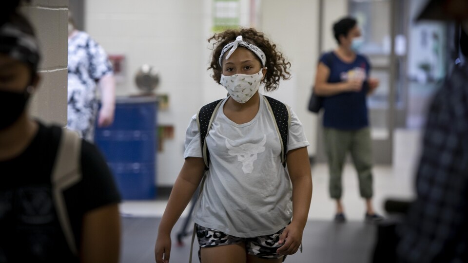 Une élève qui porte un masque arrive à l'école.