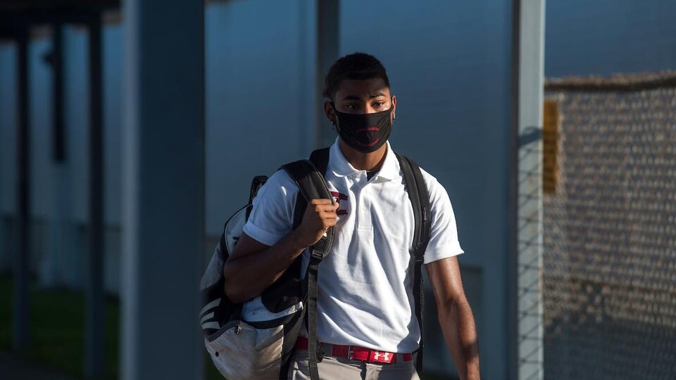Un élève du secondaire se rend à l'école avec un masque.