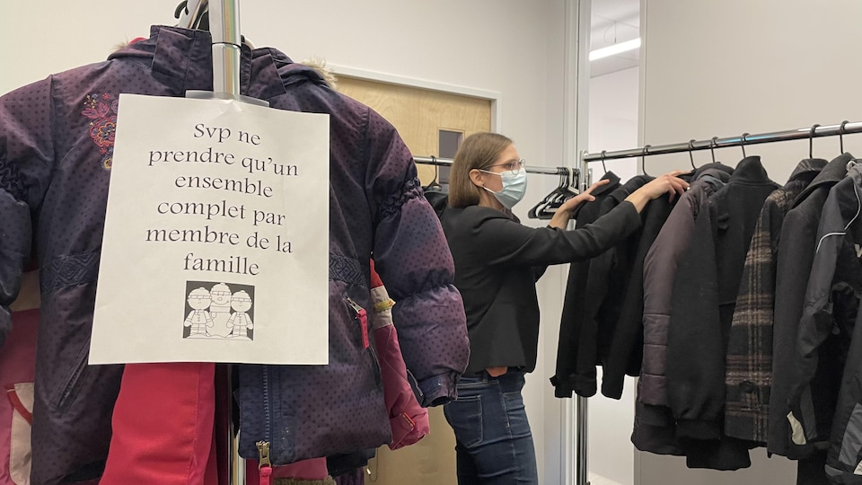 A woman puts coats in a locker room.
