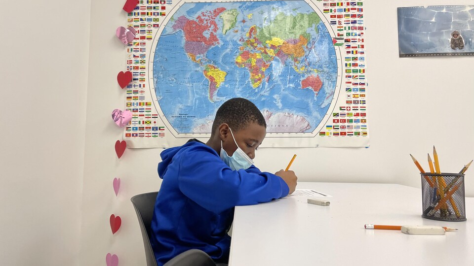 A boy is writing at his desk.