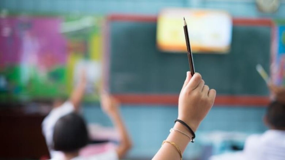 Un enfant lève la main dans une classe scolaire. 