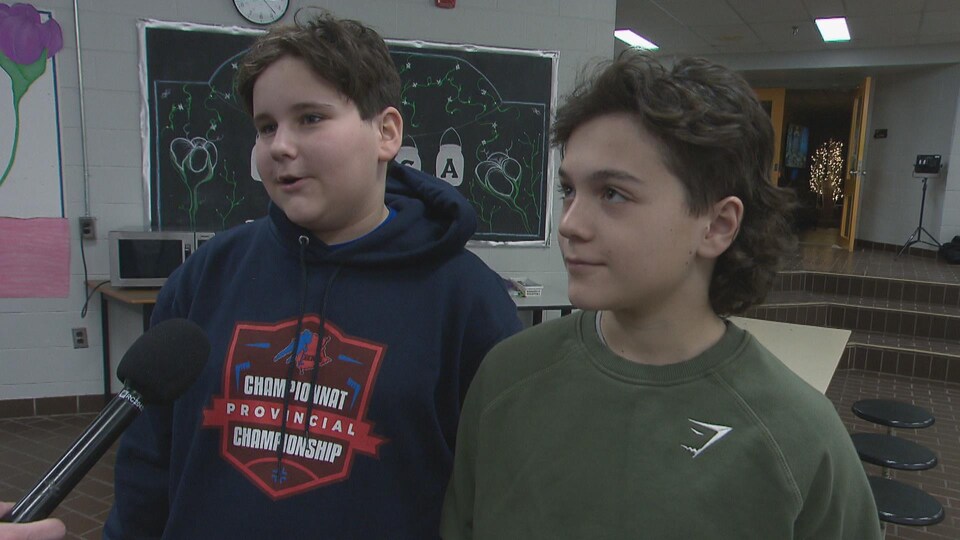 De jeunes garçons donnent une entrevue à un journaliste, dans leur école.