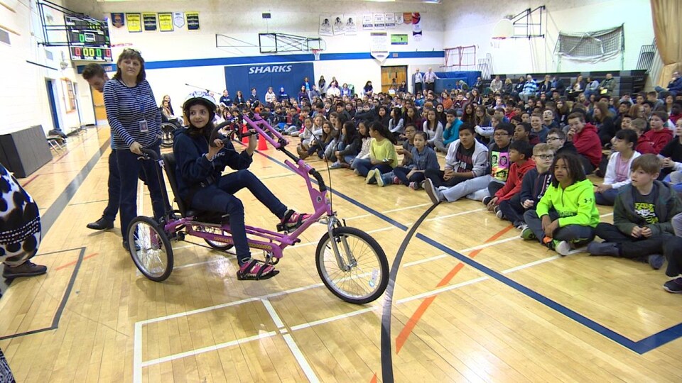 Elham Albakar, réfugiée syrienne de 12 ans qui n'est entrée à l'école que cet hiver, reçoit un vélo adapté à sa paralysie cérébrale, à Winnipeg.