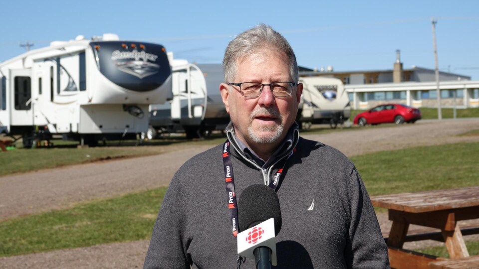 Eli Chevrier on the street, he speaks into the microphone of Radio-Canada in front of the trailers.