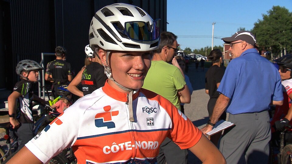 Elisabeth Martin sourit à la caméra et est coiffée d'un casque de vélo. Le logo de Loisir et Sport Côte-Nord est imprimé sur son maillot orange.