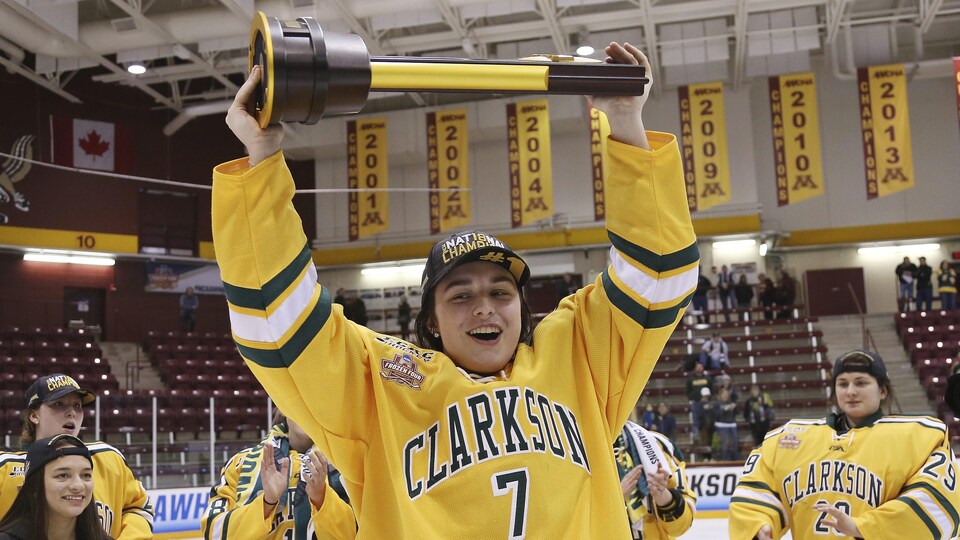 Auteure du but gagnant en prolongation, Elizabeth Giguère soulève le trophée remis à l'équipe championne du hockey universitaire américain (NCAA)
