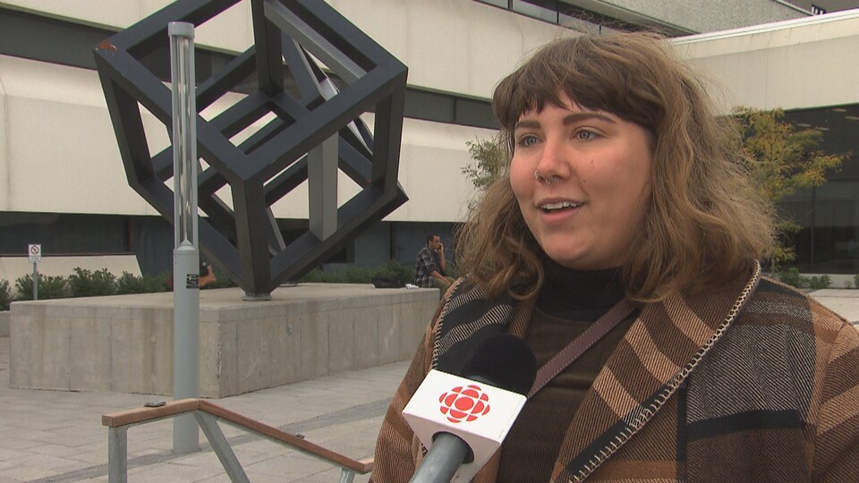 Une femme répond aux questions de la journaliste devant les cubes de l'UQTR.