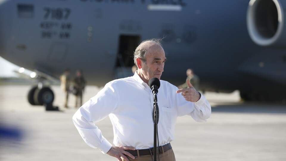 Elliott Abrams fait un point de presse sur un tarmac. Un avion de l'U.S. Air Force est stationné derrière lui.