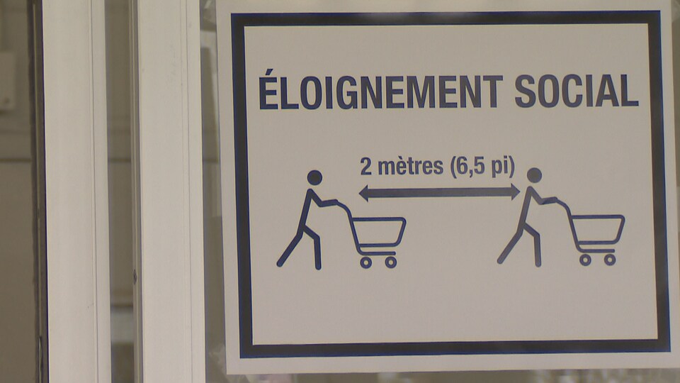 Une affiche qui demande aux clients d'une épicerie de rester à deux mètres des autres clients en raison de la pandémie de coronavirus à Québec, en mars 2020.
